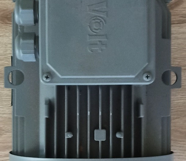 Görseldeki elektrik motoru (Volt marka) için hazırladığım bilgiler aşağıdadır:

Alternatif Metin:

Ahşap zemin üzerinde duran, gri renkli, üzerinde "Volt" markası yazılı olan bir elektrik motorunun üstten görünümü. Motorun bağlantı kutusu, kablo rakorları ve soğutma kanatçıkları görünmektedir.